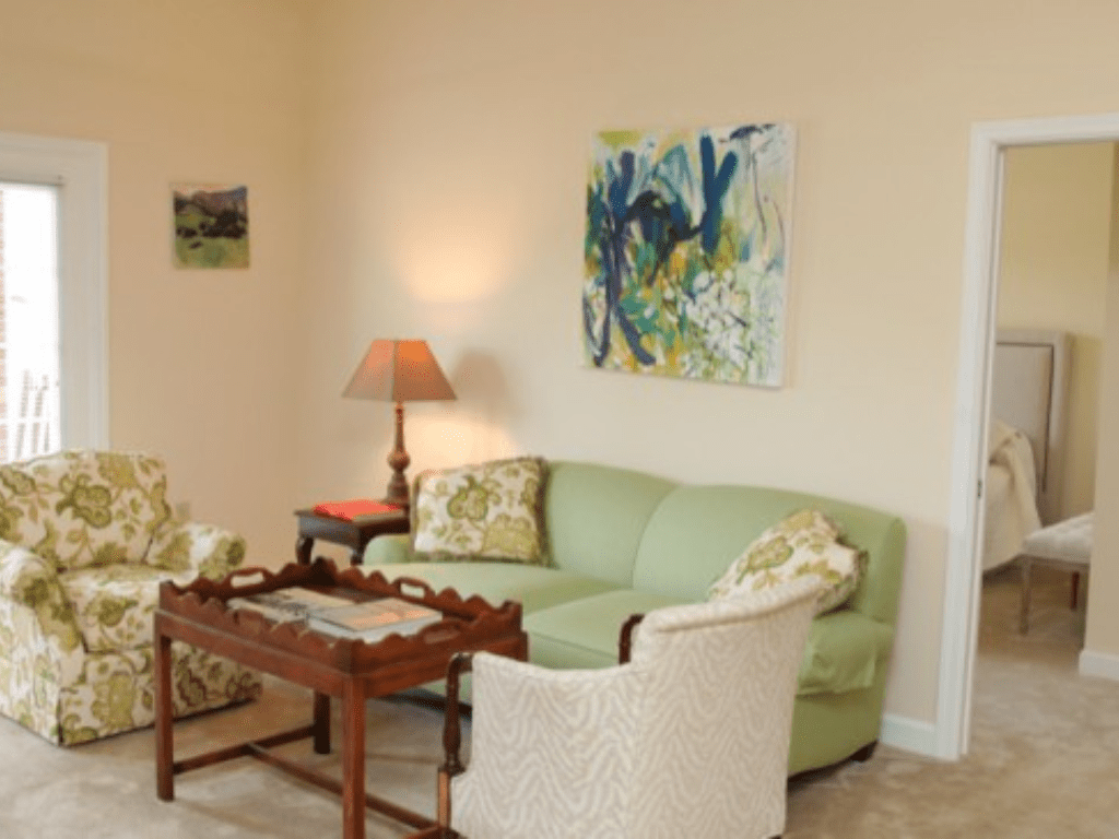 a living room with a green couch and chairs a living room with a green couch and chairs
